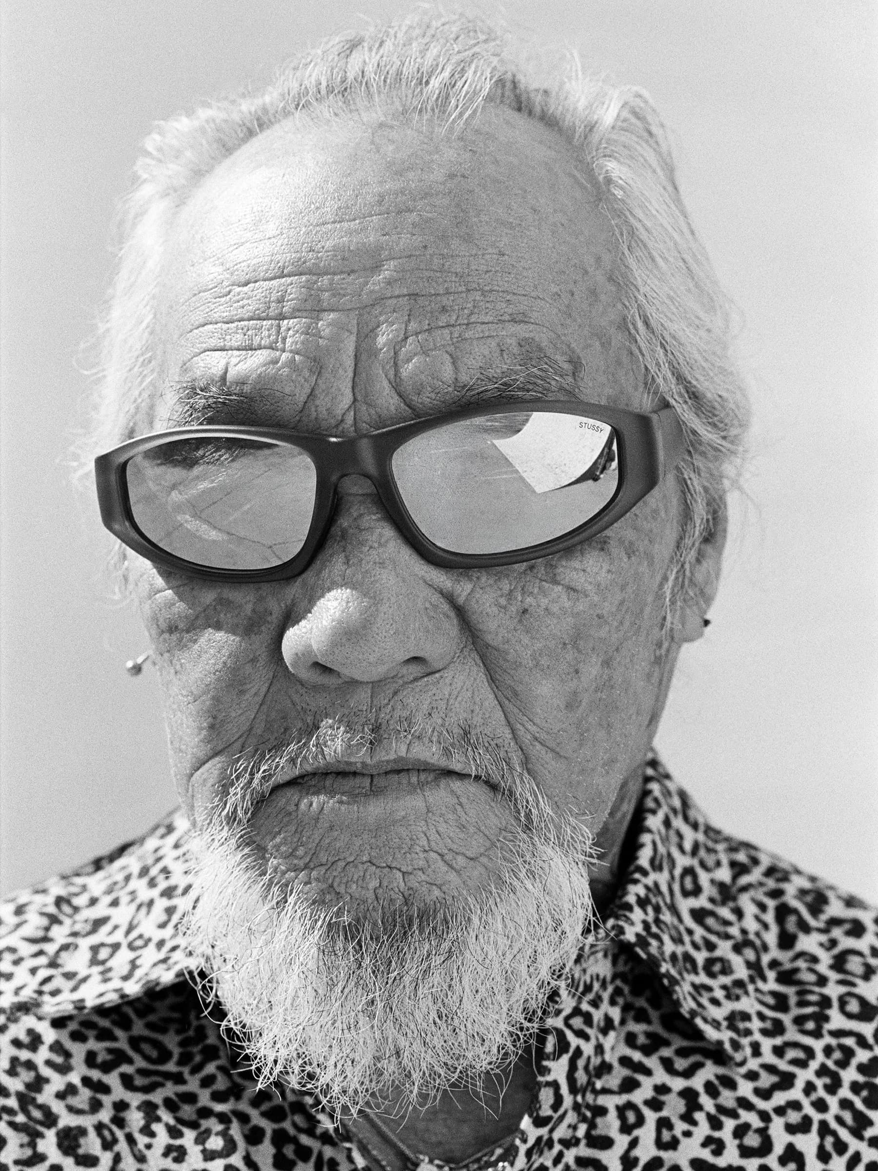 Black-and-white Stüssy campaign portrait with a skate ramp reflected in sunglasses